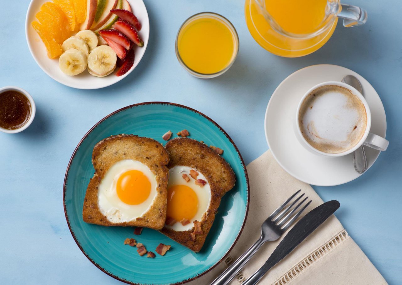 pan tostado con Nutrihuevos en el centro, café, frutas y jugo natural para el desayuno